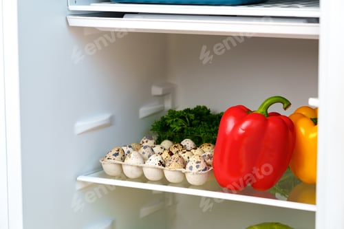 Preview: Open Refrigerator With Fresh Produce, Eggs, And A Blue Container