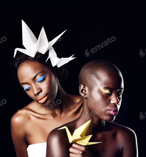 Preview: Cropped shot of two beautiful ethnic women posing with origami against a black background