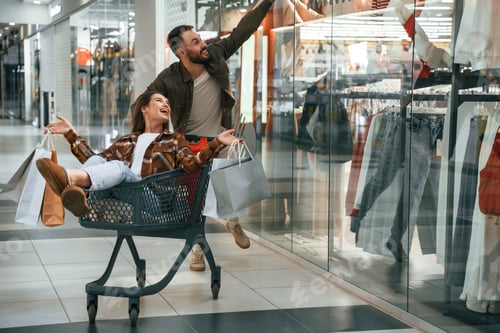 Preview: Cheerful, riding in the cart. Young couple are in supermarket together