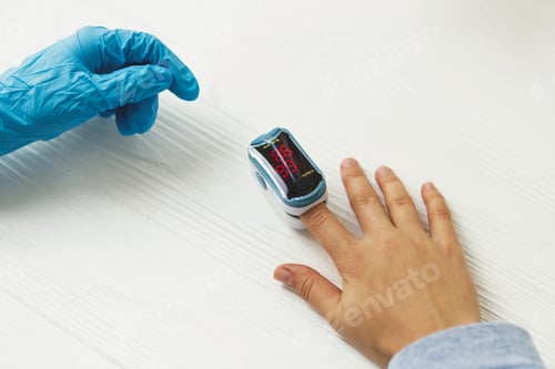 Preview: Nurse measuring blood oxygen level with portable Pulse Oximeter on hand in clinic or home