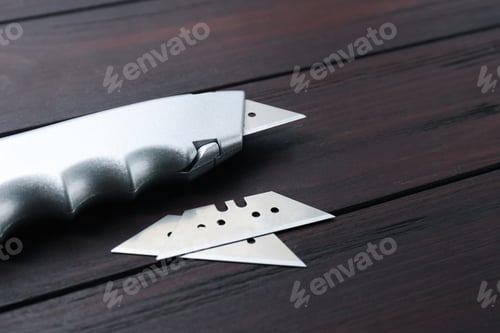 Preview: Utility knife and blades on wooden table, closeup. Space for text