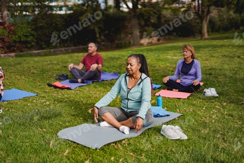 Preview: Multiracial senior people doing yoga meditation at city park - Focus at african woman