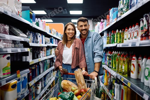Preview: Happy couple enjoying in shopping in supermarket and looking at camera.
