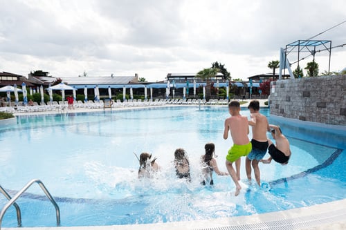 Preview: Children jumping into swimming pool with splashes of water.