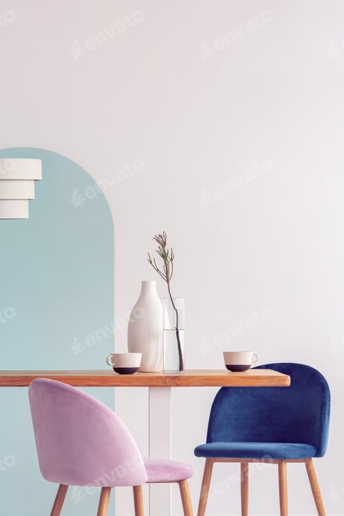 Preview: Stylish pastel pink and petrol blue chairs at long wooden table in bright dining room