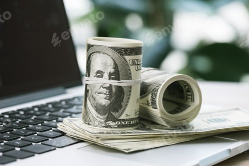 Preview: selective focus of rolled dollar banknotes on opened laptop