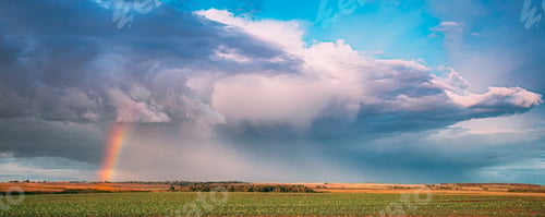 Preview: Dramatic Sky During Rain With Rainbow On Horizon Above Rural Landscape Field. Agricultural And