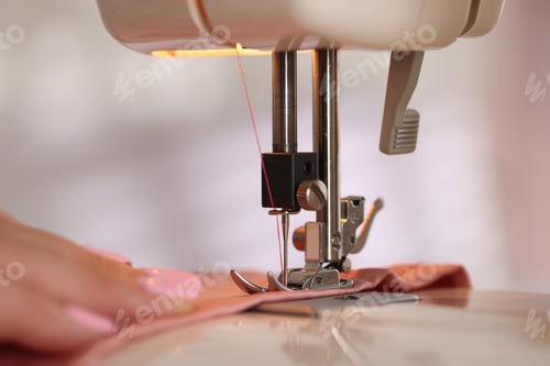 Preview: Woman working with sewing machine and fabric in workshop, closeup