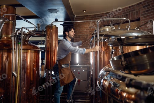 Preview: A man worker wearing an apron is diligently working in a local brewery