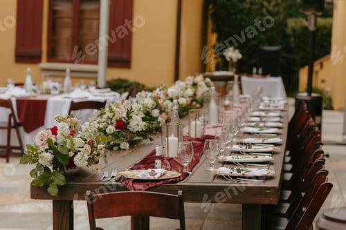 Preview: a long wooden table set with red and white flowers and place settings