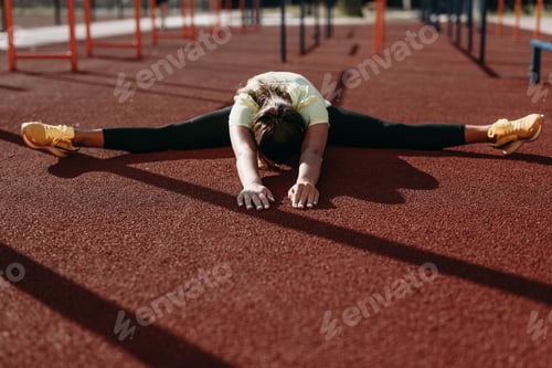 Preview: Female gymnast sitting in twine position on fresh air