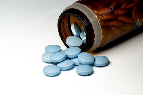 Preview: Close-up shot of blue medical tablets scattered from a jar isolated on a white background