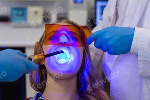 Preview: Dentists examining female patient with dental curing light