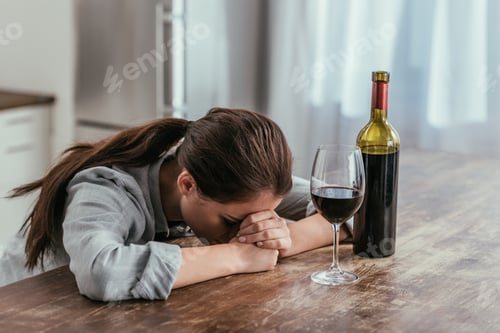 Preview: Disappointed woman beside wine glass and bottle on table