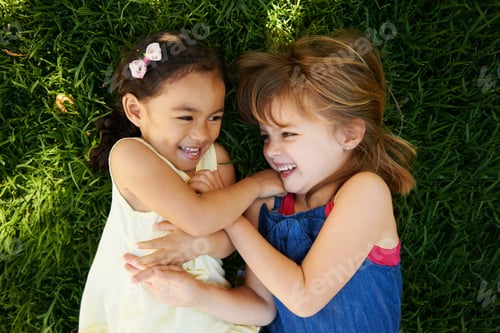 Two Happy Girls Laughing Together on Green Grass