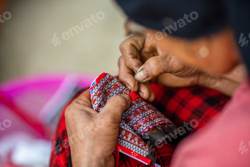 Preview: High angle shot of a middle-aged female with damaged hands making a traditional Vietnamese clothing