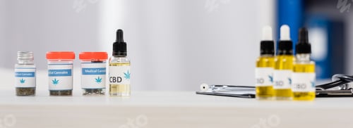 Preview: bottles with medical cannabis and cbd lettering near clipboard on desk in clinic, banner