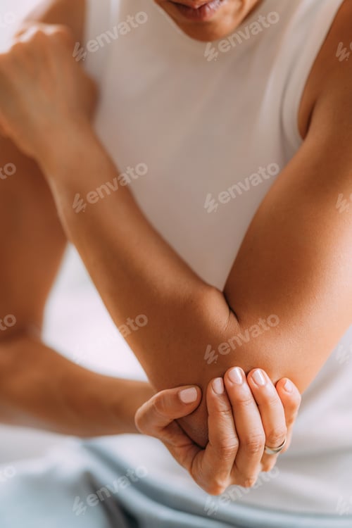 Adult Holding Elbow Joint in Soft Light