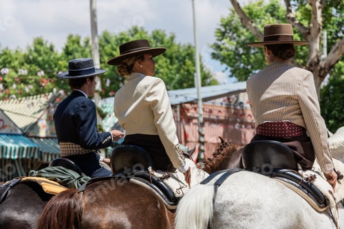 Preview: Ethnic woman in hat sitting on horseback with friends in daylight