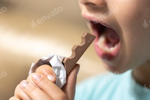 Preview: Detailed shot of a girl bites a chocolate bar.
