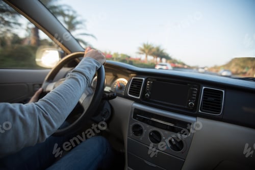 Preview: Hands on wheel driving car in morning tropical city