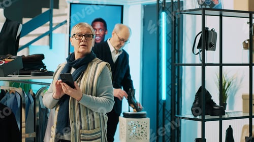 Preview: Elderly woman checking website stock to find items in store at mall