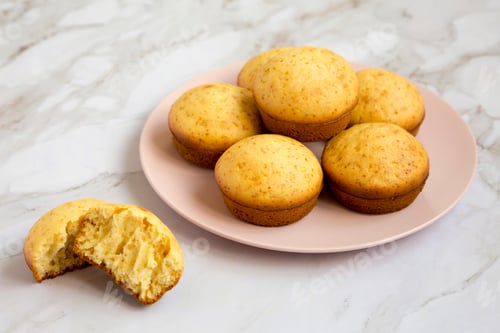 Preview: Homemade Cornbread Muffins on a pink plate, side view.