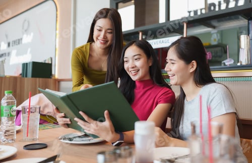 Preview: Asian friends choosing food from restaurant menu