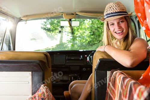 Preview: Woman leaning over driver seat in campervan wearing straw hat and polka dot blouse, copy space
