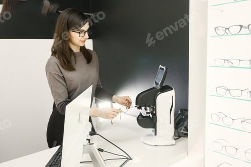 Preview: Professional female optician checking eyeglasses in special machine