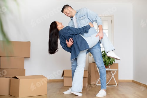 Preview: Romantic young couple dancing in room with cardboard boxes on moving day