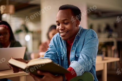 Preview: Happy black college student learning from a book at campus.