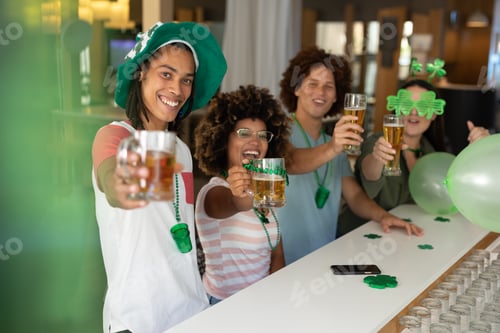 Preview: Diverse group of happy friends celebrating st patrick's day raising glasses of beer at a bar