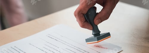 Preview: Businessman is stamping a piece of paper with a red stamp.