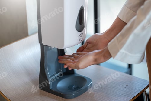 Preview: Close up of hand placed under the automatic alcohol dispenser to prevent pathogens In public areas.