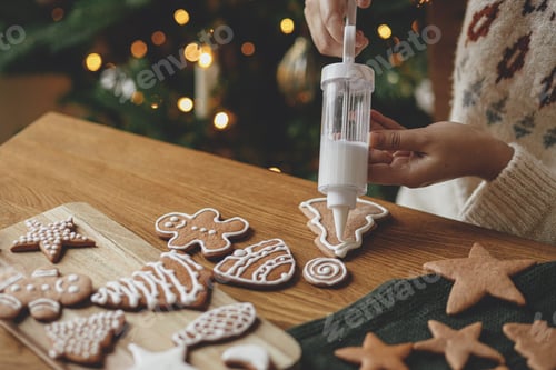 Preview: Hands decorating gingerbread cookies with icing and cute dog helping tasting and licking sugar paste
