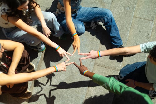 Preview: Students wearing rainbow bracelets forming star shape with fingers