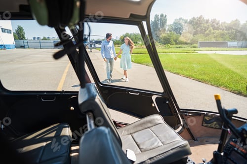 Preview: Smiling woman and man walking towards helicopter