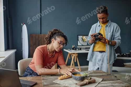 Preview: Young Adult Black Woman Arranging Bread While Young Adult Black Man Photographing