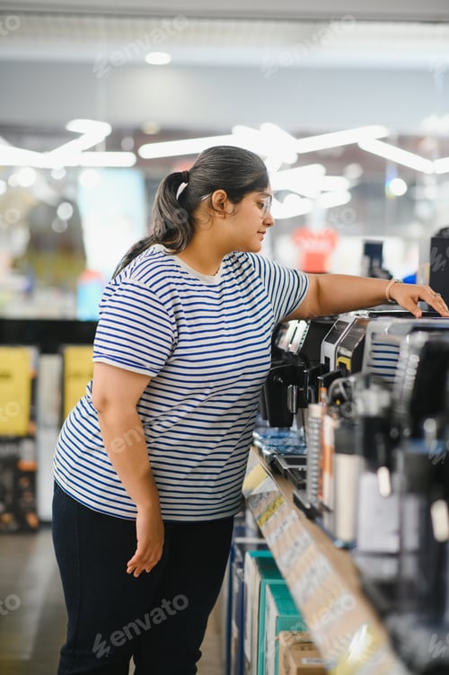 Preview: Smart modern female customer choosing coffee machine at electronics store