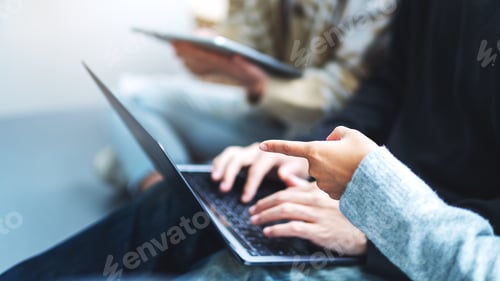Preview: A group of young people sitting and using laptop computer and digital tablet together