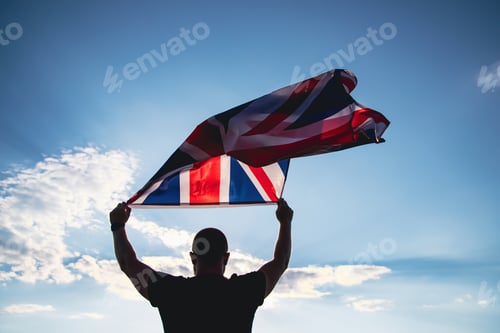 Preview: Man holding British flag against blue sky