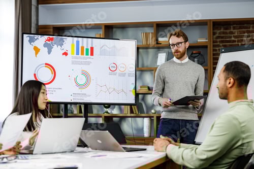 Preview: Motivated team leader explaining company development strategy to smiling young multinational