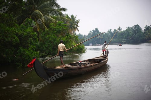 Preview: Two men navigating a river on a traditional wooden canoe surrounded by lush greenery.