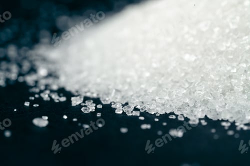 Preview: close-up on a black-blue background white crumbly granulated sugar lies on it, crystal lumps around