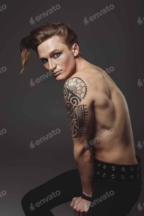 Preview: shirtless tattooed male model with strange hairstyle, isolated on grey