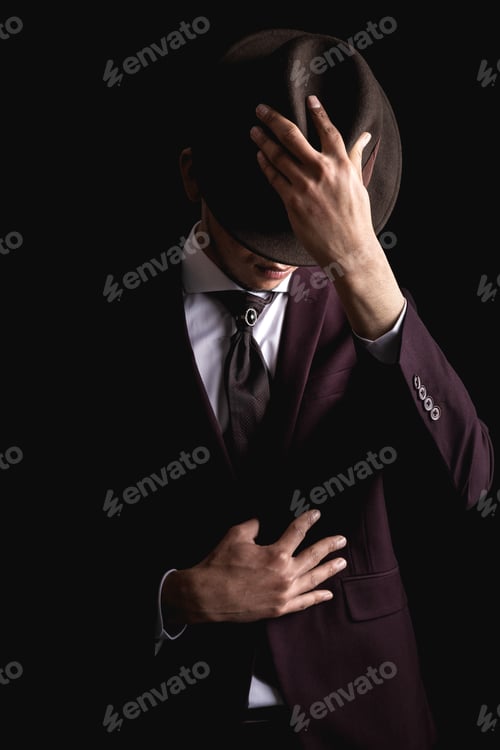 Preview: Latin man in suit on black background with hands on hat