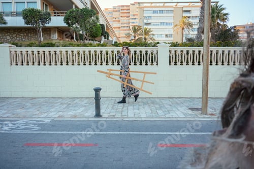 Preview: Woman Walking Down Sidewalk Next to Tall Building with a Easel