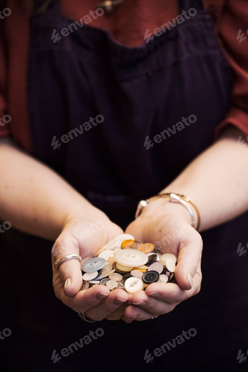 Preview: A woman holding hands full of buttons, varied shapes and sizes.