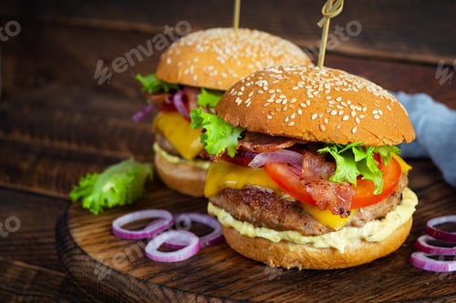 Preview: Delicious beef hamburger with bacon slice, cheese, lettuce and tomato. Tasty fastfood burger